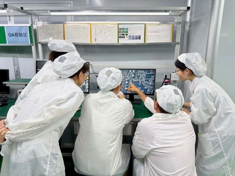 OQC 3D Microscope Review at STHL Two visitors from Russia reviewing magnified PCBA images at STHL's outgoing quality control workstation